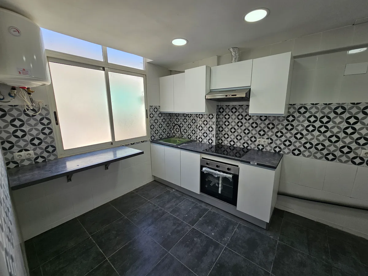 Cocina reformada en Catarroja con muebles blancos, encimera oscura y salpicadero hidráulico